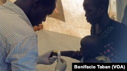 FILE - A health worker prepares to give medication intravenously to a South Sudanese child who has tested positive for malaria, in the Ayilo refugee resettlement camp in Uganda.