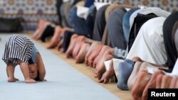 FILE - A child is seen near members of the Muslim community attending midday prayers at Strasbourg Grand Mosque in Strasbourg, France, on the first day of Ramadan.