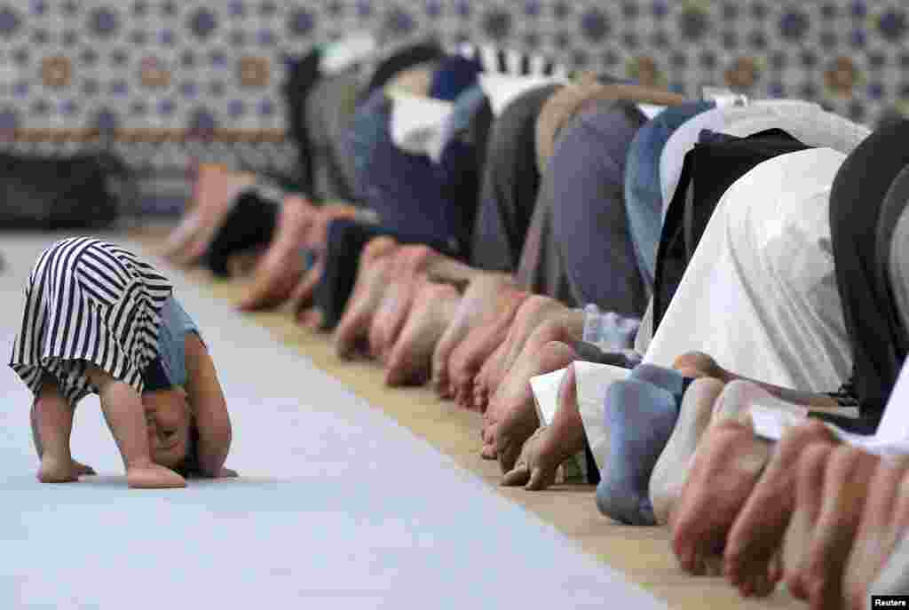 A child is seen near members of the Muslim community attending midday prayers at Strasbourg Grand Mosque in Strasbourg, France, on the first day of Ramadan, July 9, 2013.
