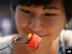 Amornrat Simapsaisan, a local shop manager, eats a watermelon salad with bamboo worms at Insects in the Backyard restaurant, in Bangkok, Thailand, Sept. 12, 2017.