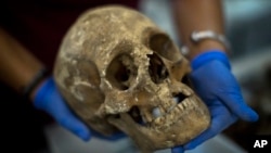 In this Tuesday, Aug. 28, 2018 photo, a victim's skull is examined during the classification process by anthropologists following the exhumation of a mass grave found in 2018 at the cemetery of Paterna, near Valencia, Spain.