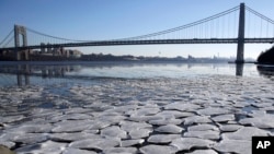 A layer of ice is broken into pieces floating along the banks of the Hudson River at the Palisades Interstate Park with the George Washington Bridge in the background, Jan. 2, 2018, in Fort Lee, New Jersey. 