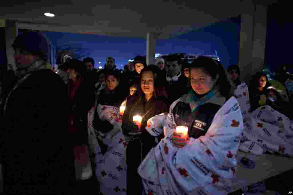 Penduduk setempat berdoa bersama di luar SMU Newtown, seusai Presiden Barack Obama menyampaikan sambutannya dalam acara doa bersama lintas agama untuk para korban penembakan Sekolah Dasar Sandy Hook, Newtown, Connecticut, 16 Desember 2012. (AP Photo/Evan Vucci)