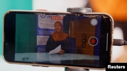 FILE - Fathi Mohamed Ahmed, a journalist at Bilan Media, Somalia's first all-women media team, uses a mobile telephone to record the news, inside the Bilan Media studios in Mogadishu, Somalia August 20, 2023.