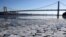 A layer of ice is broken into pieces floating along the banks of the Hudson River at the Palisades Interstate Park with the George Washington Bridge in the background, Jan. 2, 2018, in Fort Lee, New Jersey. 