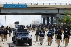 Police officers fire teargas as they move to disperse the supporters of the Tehreek-e-Labaik Pakistan (TLP) Islamist political party during a protest against the arrest of their leader, in Peshawar, Pakistan, Apr. 13, 2021.