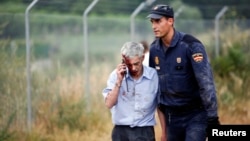 An injured man, identified by Spanish newspapers as the train's driver, Francisco Jose Garzon, is helped by a policeman after the crash near Santiago de Compostela, northwestern Spain, July 24, 2013.