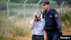 An injured man, identified by Spanish newspapers El Pais and El Mundo as the train driver Francisco Jose Garzon, is helped by a policeman after a train crashed near Santiago de Compostela, northwestern Spain, July 24, 2013.