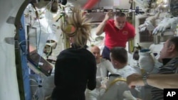 In this image from video made available by NASA, astronauts discuss the aborted spacewalk aboard the International Space Station, July 16, 2013. A dangerous water leak in the helmet of Luca Parmitano, bottom center facing camera in white suit, drenched his eyes, nose and mouth, preventing him from hearing or speaking as what should have been a routine spacewalk came to an abrupt end.
