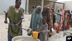 Somalis from southern Somalia receive food at a camp in Mogadishu distributed by the Jumbo organization, a local NGO, in Mogadishu, Somalia, after fleeing from southern Somalia, Thursday, July 7, 2011.