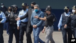 FILE - Former Honduran President Juan Orlando Hernandez, center, is taken in handcuffs to a waiting aircraft as he is extradited to the United States, at an air force base in Tegucigalpa, Honduras, April 21, 2022. 