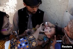 Vaccination workers give a boy polio vaccine drops on a street in Quetta, Pakistan, Jan. 2, 2017.