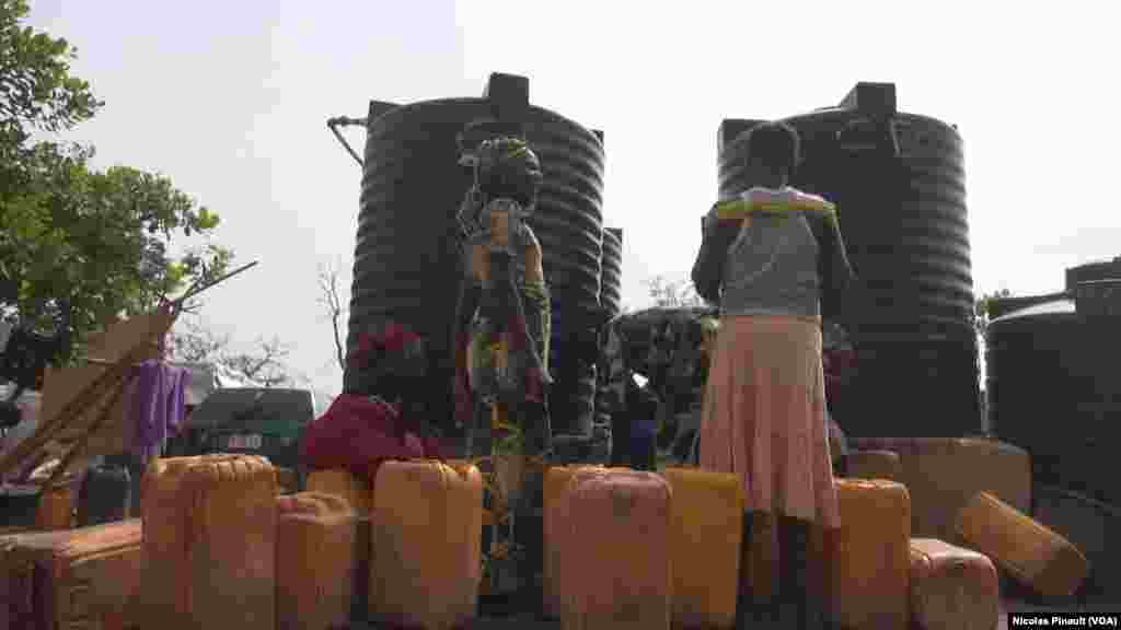 Women wait to fill their jugs with water at the New Kuchogoro camp in Abuja, March 7, 2016. (N. Pinault / VOA)