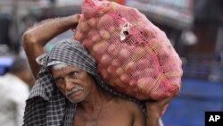 An Indian laborer carries a bag full of potatoes at a warehouse in Jammu, India, July 31,2012.