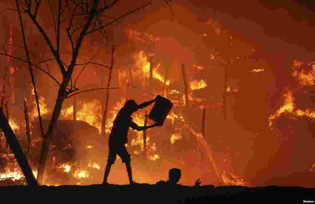 A man tries to extinguish a fire that broke out in a slum area in the eastern Indian city of Bhubaneswar.