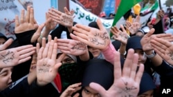 Iranian schoolgirls show their hands with pro-government slogans and an anti-Israeli slogan that reads in Farsi: "Death to Israel," during a rally in front of the former U.S. Embassy in Tehran, Iran, on Nov. 4, 2023.