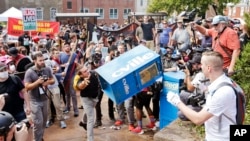 White nationalist demonstrators, right, clash with a counter demonstrator as he throws a newspaper box at the entrance to Lee Park in Charlottesville, Virginia, Aug. 12, 2017. The deadly white nationalist demonstration in Virginia has brought new attention to an anti-fascist movement whose members have been a regular presence at protests around the country in the last year.