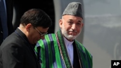 Afghanistan President Hamid Karzai (R) steps off an airplane after arriving in New Delhi, October 4, 2011.