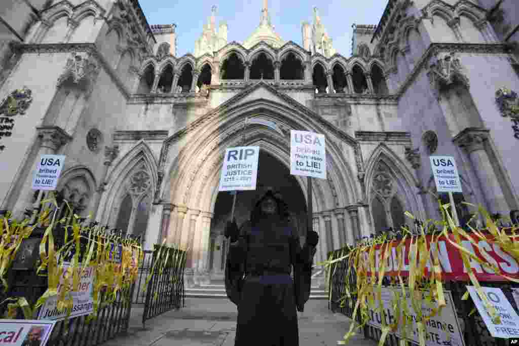 A protestor demonstrates outside the High Court in London after the court overturned an earlier decision that barred WikiLeaks founder Julian Assange from being sent to the US to face espionage charges.