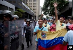Opposition leader Leocenis Garcia, right, with members of his party, shout slogans against Venezuela's President Nicolas Maduro outside the attorney general's office, where police stand guard, in Caracas, Venezuela, July 18, 2018.