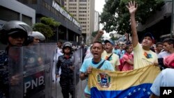 Opposition leader Leocenis Garcia, right, with members of his party, shout slogans against Venezuela's President Nicolas Maduro outside the attorney general's office, where police stand guard, in Caracas, Venezuela, July 18, 2018. The previous night, another opposition leader, Henrique Capriles, called on the country's political forces to reorganize in order to cope with the South American country's hyperinflation, and lack of food and medicine.