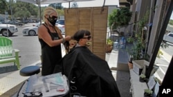 Laure Chicoine, owner of Nirvana hair salon, gives an outdoor haircut in the parking lot behind her shop on Wednesday, July 22, 2020, in Los Gatos, Calif. (AP Photo/Ben Margot)
