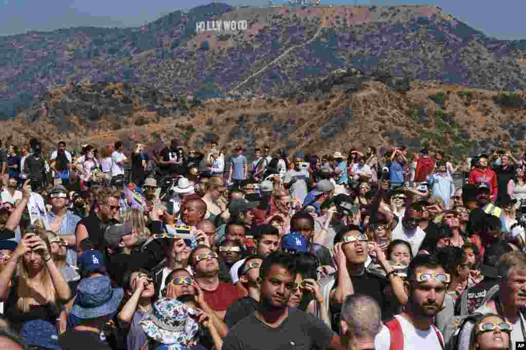A large crowd gathers in front of the Hollywood sign at the Griffith Observatory to watch a partial solar eclipse in Los Angeles, California.