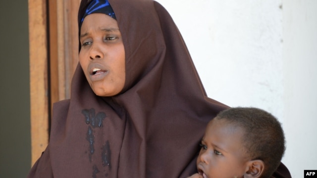 FILE - A Somali woman, who was sentenced to a year in jail after she told a reporter she was raped by security forces, holds her baby at the court house in Mogadishu, March 3, 2013.