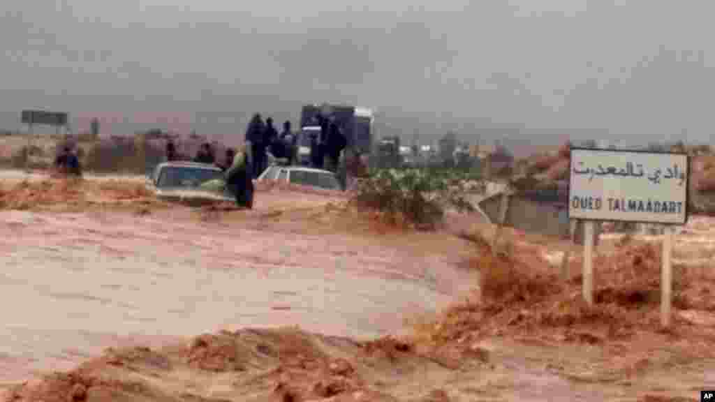 Cette image prise avec un téléphone portable montre résidents de Guelmim, au sud ouest du Maroc, des passagers sont coincés sur des véhicules bloqués par la montée des eaux, lundi 24 novembre 2014.