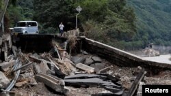 A man stands next to a damaged road after floods caused by torrential rain, in Kumamura, Kumamoto Prefecture, southwestern Japan, July 8, 2020. (REUTERS/Kim Kyung-Hoon)