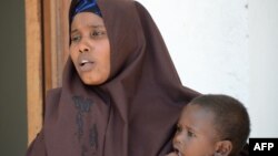 FILE - A Somali woman, who was sentenced to a year in jail after she told a reporter she was raped by security forces, holds her baby at the court house in Mogadishu, March 3, 2013.