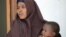 FILE - A Somali woman, who was sentenced to a year in jail after she told a reporter she was raped by security forces, holds her baby at the court house in Mogadishu, March 3, 2013.