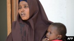 FILE - A Somali woman, who was sentenced to a year in jail after she told a reporter she was raped by security forces, holds her baby at the court house in Mogadishu, March 3, 2013.