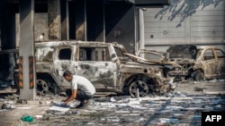 A man collects files next to the wreckage of burned vehicles at the Rwandan Embassy a day after an attack on the building during a demonstration against the escalating conflict in eastern Democratic Republic of Congo in Kinshasa, on Jan. 29, 2025.