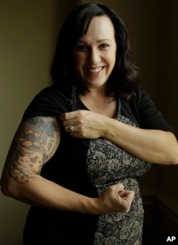 MJ Hegar pulls up her sleeve to reveal part of a tattoo that winds around her arm and back, for a portrait at her home in Round Rock, Texas, Aug. 9, 2018. Nine years after being shot down in Afghanistan, winning a lawsuit against the federal government, and writing a book, Hegar is now running for a Texas congressional seat.
