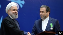 Iranian President Hassan Rouhani, left, shakes hand with Iran's deputy Foreign Minister and senior nuclear negotiator Abbas Araghchi after awarding him a medal of honor in a ceremony in Tehran, Iran, Feb. 8, 2016. 