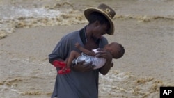 A man carries a child while wading across a flooded street during the passing of Hurricane Tomas in Leogane, Haiti, 05 Nov 2010