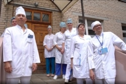 In this photo made from footage provided by the Russian Defense Ministry on July 15, 2020, medical workers look at volunteers participating in a coronavirus vaccine trial as they leave the Budenko Main Military Hospital outside Moscow, Russia.
