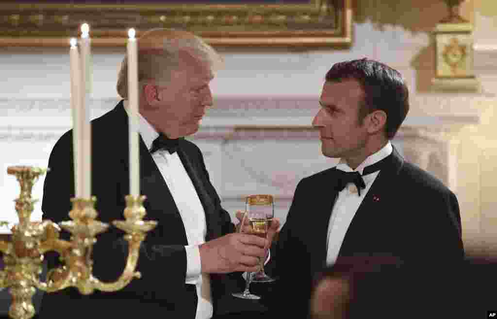 Presiden Donald Trump, kiri, dan Presiden Perancis Emmanuel Macron, kanan, saling bersulang dalam Makan Malam Kenegaraan di Gedung Putih, 24 April 2018.