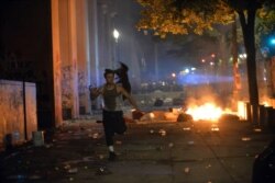 FILE - A man runs as several protesters manage to breach the fence and enter the portico of the Multnomah County Justice Center in Portland, Oregon, July 23, 2020.
