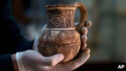 Jihad Abu Kahrlah, an archeologist at Syria's National Museum, holds an artifact delivered from the Daraa Museum to Damascus, Syria, Feb. 23, 2016. Faced with the Islamic State group onslaught and destruction by looters, Syrian antiquities authorities succeeded in evacuating hundreds of thousands of artifacts from museums around the country to safety in Damascus. 