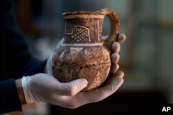 Jihad Abu Kahrlah, an archeologist at Syria's National Museum, holds an artifact delivered from the Daraa Museum to Damascus, Syria, Feb. 23, 2016. Faced with the Islamic State group onslaught and destruction by looters, Syrian antiquities authorities are sending them away for safety.