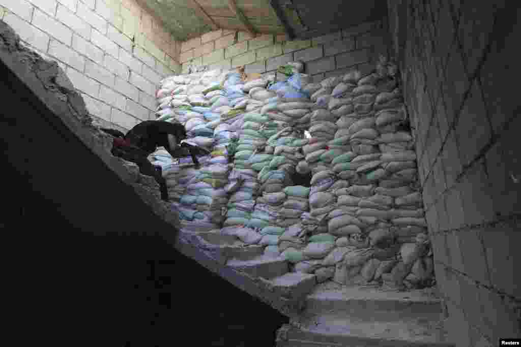 A member of the Shohadaa Badr Brigade, which operates under the Free Syrian Army, stands in shooting position behind sandbags in Ashrafieh, Aleppo, September 17, 2013.
