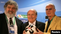 Le Président de la FIFA Sepp Blatter, Franz Beckenbauer, président du comité local d'organisation et Chuck Blazer, président de la Coupe des Confédérations au sein de la FIFA présentent le ballon officiel de la compétition lors d'une conférence de presse à Francfort le 13 juin 2005. (REUTERS / Kai Pfaffenbach)