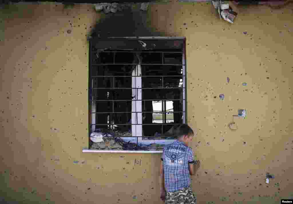 A boy collects bullets and empty cartridges next to abandoned buildings of the Ukrainian border guard regional headquarters damaged in a recent fight with pro-Russian separatists, on the outskirts of the eastern Ukrainian city of Luhansk.