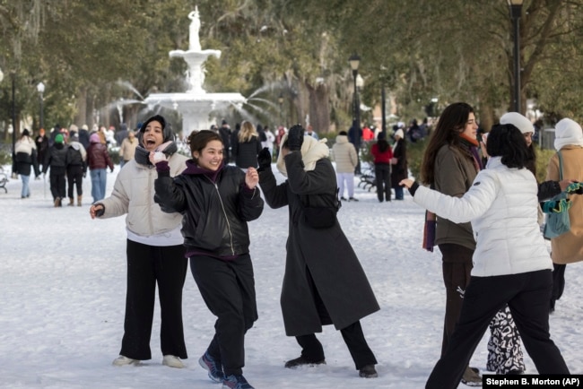 A group of Savannah College of Art and Design students have a snowball fight near the historic fountain at Forsyth Park, Wednesday, Jan. 22, 2025, in Savannah, Ga.