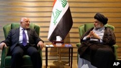 In this photo provided by the Iraqi government, Iraqi Prime Minister Haider al-Abadi, left, meets with Shi'ite cleric Muqtada al-Sadr in the heavily fortified Green Zone in Baghdad, May 20, 2018.
