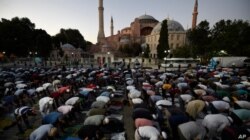 FILE - Muslims offer their evening prayers outside the Byzantine-era Hagia Sophia, one of Istanbul's main tourist attractions in the historic Sultanahmet district of Istanbul, July 10, 2020.