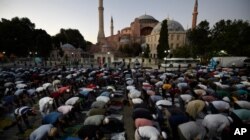 FILE - Muslims offer their evening prayers outside the Byzantine-era Hagia Sophia, one of Istanbul's main tourist attractions in the historic Sultanahmet district of Istanbul, July 10, 2020.