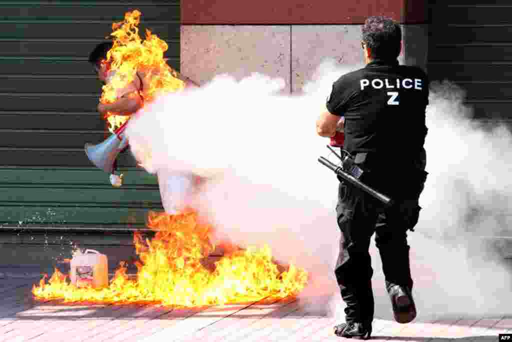 September 16: A police officer extinguishes a man who set himself on fire outside a branch of Piraeus bank in Thessaloniki, Greece. The former small business owner says he was ruined after taking a series of bank loans. (AP Photo/Nontas Stlianidis)